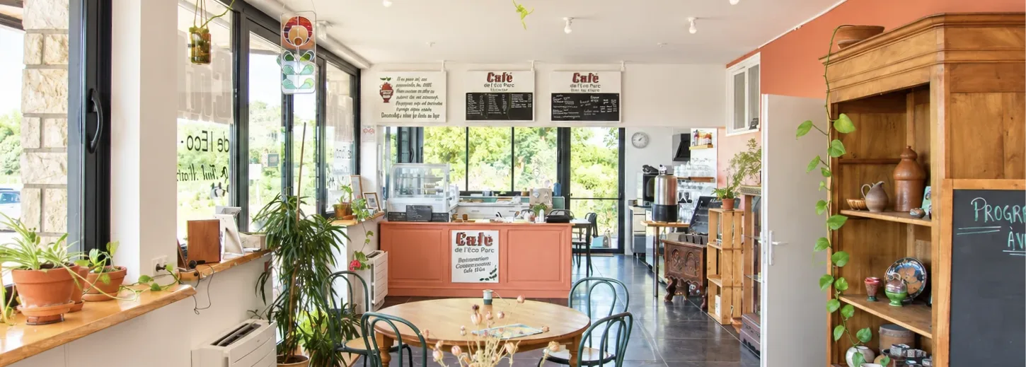 Intérieur du café-restaurant avec tables, plantes et comptoir